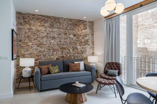 a living room with a blue couch and a brick wall at Homely Málaga Mariblanca 17, Vegafuente Apartments in Málaga