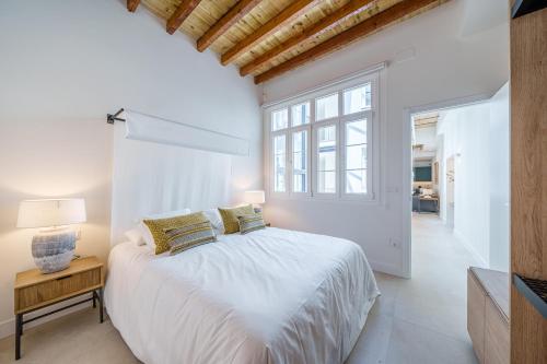 a white bedroom with a large bed and a window at Homely Málaga Mariblanca 17, Vegafuente Apartments in Málaga