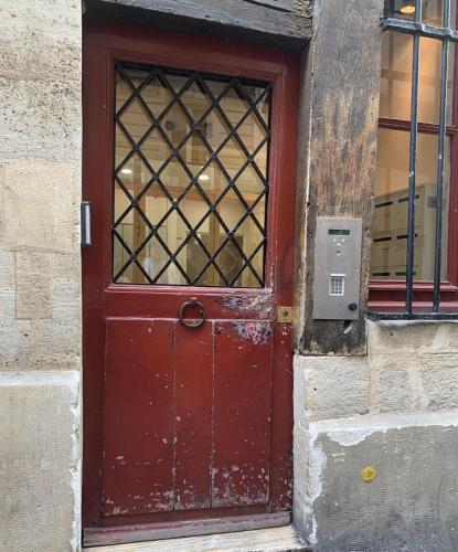 a red door on a building with a window at BEST CENTRAL Chambres Privées - Seine & Louvre in the Connected Heart of Paris in Paris
