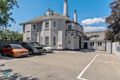 una gran casa blanca con coches aparcados en un aparcamiento en 2 Bed- The Penthouse By Pureserviced, en Plymouth