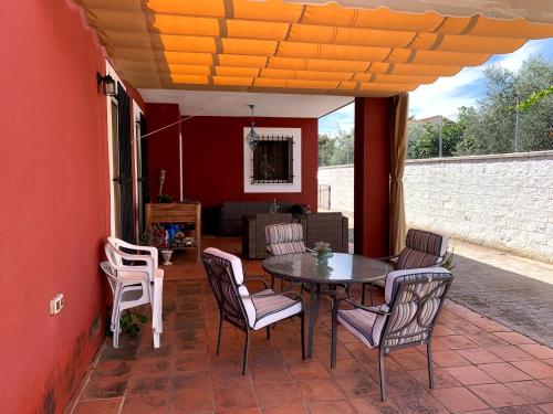 een patio met een tafel en stoelen aan een rode muur bij Casa situada en un entorno natural Casa Rural La Serena in Trujillo