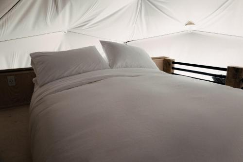 uma cama branca com lençóis e almofadas brancos em Les diamants de l'éternel em Saint-David-de-Falardeau