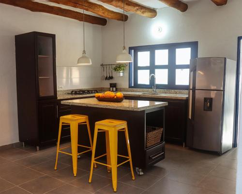 a kitchen with two yellow bar stools and a refrigerator at Unique House Elena Barichara Open Space Bright in Barichara