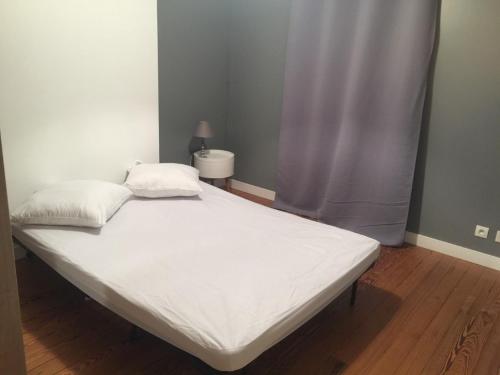 a bed with white sheets and pillows in a room at Le 64 MONTALIEU SEJOUR, Appartement 4 pers in Montalieu-Vercieu