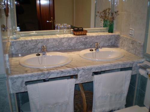 2 lavabos en un baño con 2 espejos en Hotel L'Ablana en Pola de Somiedo