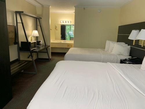 Habitación de hotel con 2 camas y espejo en Americas Best Value Inn & Suites Melbourne, en Melbourne