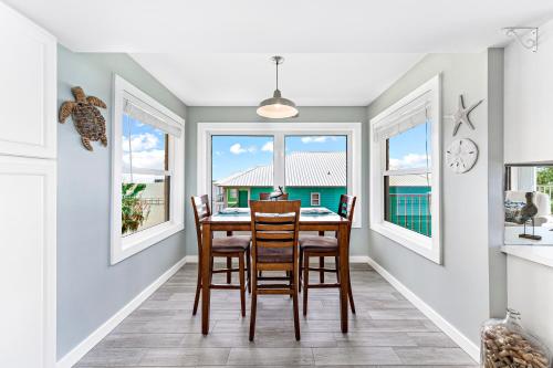 a dining room with a table and chairs and windows at Compass Point 310 in Gulf Shores