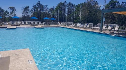 a large pool of blue water with chairs and blue umbrellas at Eagle Cottages & The Cabins at Gulf State Park in Gulf Shores
