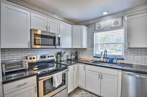 a kitchen with white cabinets and stainless steel appliances at New Smyrna Beach Townhome, Walk to Bay Access! in New Smyrna Beach