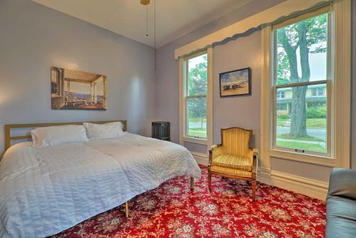 a bedroom with a bed and a chair and windows at Coastal Grand - Walk to Lake Michigan! in Ludington