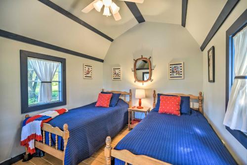 two beds in a room with blue sheets and red pillows at Quiet Lakeside Cabin Patio and Stunning Views! in Grantsburg