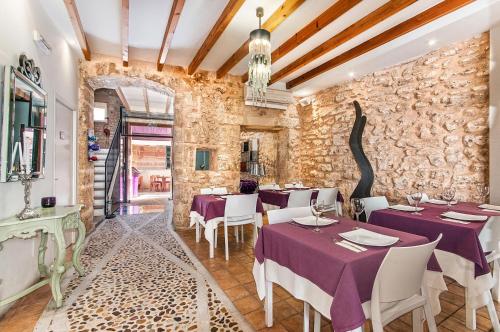 a restaurant with purple tables and chairs and a stone wall at Ca´n Pere in Alcudia