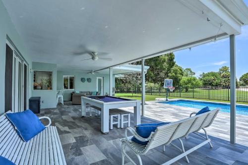 a patio with a ping pong table and chairs next to a pool at Jupiter Home with Private Pool and Putting Green! in Jupiter