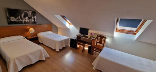 um quarto com 2 camas, uma secretária e uma janela em Hostal Santo Tomé em Toledo