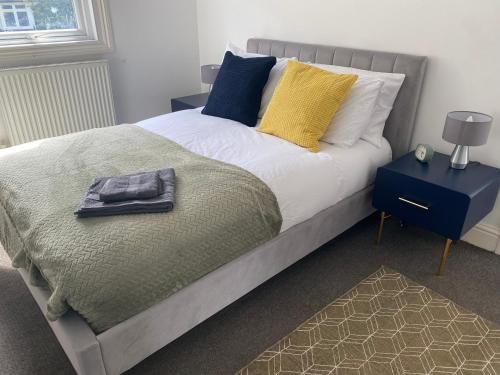 Una cama con almohadas amarillas y azules encima. en Palm Bay Apartment, en Margate