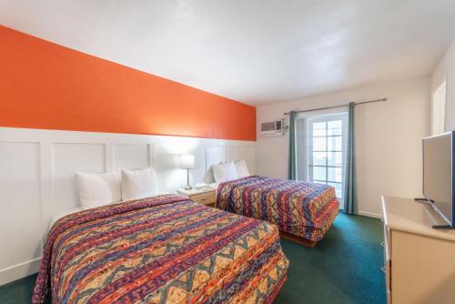 a hotel room with two beds and a flat screen tv at Captain's Table Hotel by Everglades Adventures in Everglades City