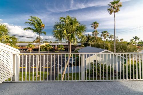 a white fence with palm trees in the background at Captain's Table Hotel by Everglades Adventures in Everglades City