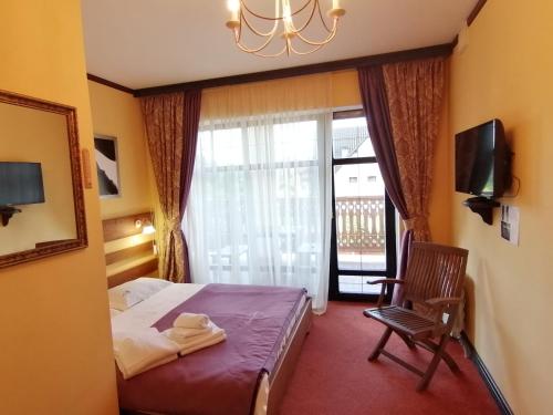 ein Schlafzimmer mit einem Bett, einem Stuhl und einem Fenster in der Unterkunft Шале Золота пiдкова та рiчка in Slawske