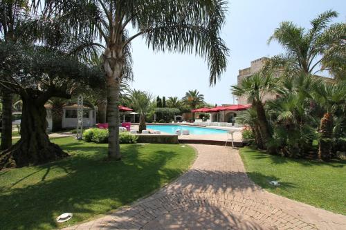 een resorttuin met een zwembad en palmbomen bij Hotel & Resort Lunatenuta in Mondragone