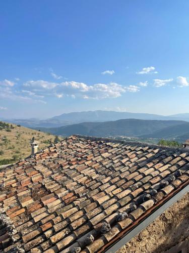 an old tile roof with mountains in the background at La casa di mezzo in Calascio