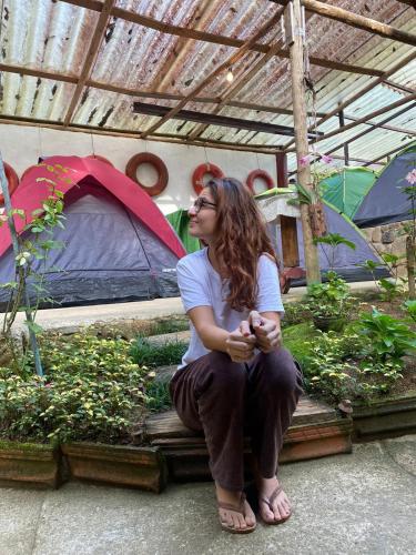 a woman sitting on a bench in a garden at Ready Camp e Suítes da Cachoeira in Abraão