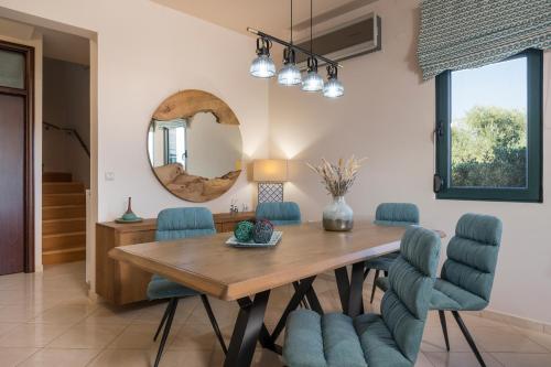 jadalnia z drewnianym stołem i niebieskimi krzesłami w obiekcie Antonia Blue Villa w mieście Mourniaí