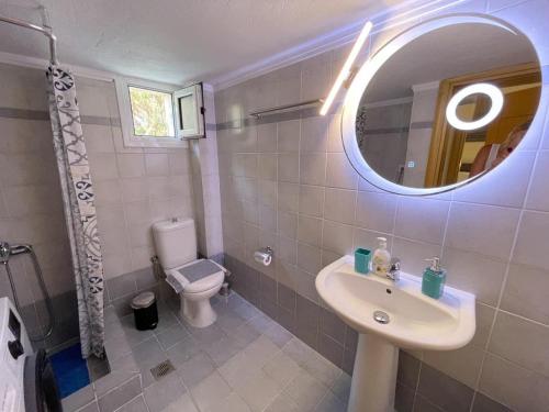 W łazience znajduje się umywalka, toaleta i lustro. w obiekcie Elena apartment chalkidiki w mieście Kallithea