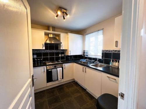 una cucina con armadi bianchi e lavandino di 4 Bedroom house for Contractors,family,free parking,study,internet in ipswich a Ipswich