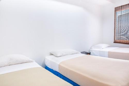 3 camas en una habitación con ventana en Cabañas Santorini Santa Marta, en Santa Marta