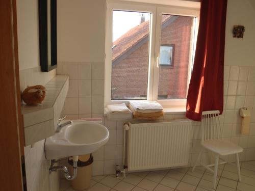 a bathroom with a sink and a window and a chair at Triton II in Hohwacht