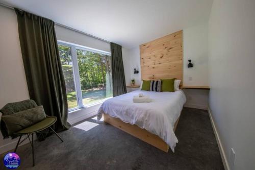 - une chambre avec un grand lit et une chaise dans l'établissement Chalet Forestria - SPA- Billard- Ski, à Mansonville