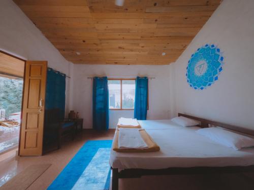 Shiv Shakti Yogpeeth Cottages في ريشيكيش: غرفة نوم بسرير وسقف خشبي