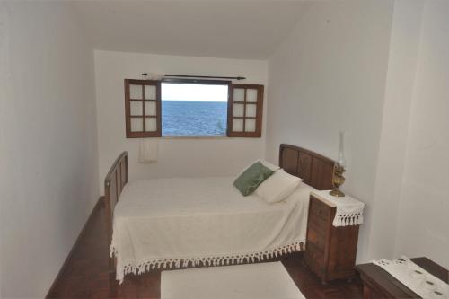 ein kleines Schlafzimmer mit einem Bett und einem Fenster in der Unterkunft Casa da Salga in Angra do Heroísmo