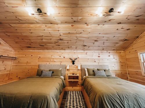 two beds in a room with wooden walls at Cabin #8 Studio With Kitchenette in Hartwell