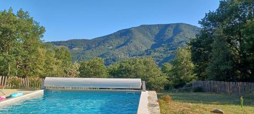 a large swimming pool with a mountain in the background at Le Mas De La Siffleuse in Jaujac