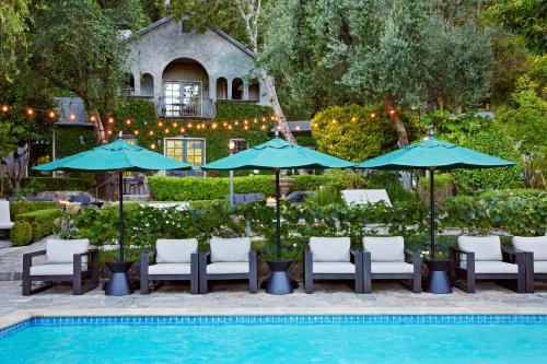 a pool with chairs and umbrellas next to a house at Kenwood Inn & Spa in Kenwood