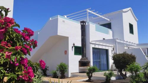 a white house with flowers in front of it at Hyde Park Lane in Puerto del Carmen