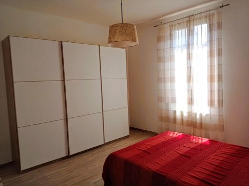 a bedroom with white cabinets and a red bed at SANTA MARIA HOUSE in Empoli
