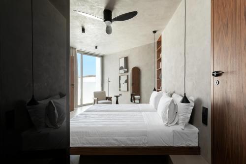 a bedroom with a bed with a ceiling fan at PNOĒS Tinos in Tinos Town