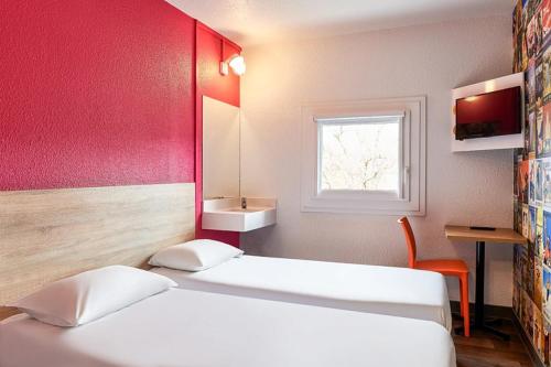 two beds in a room with a red wall at hotelF1 Marne la Vallée Collégien in Collégien