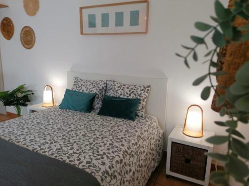 a bedroom with a bed with green pillows and two lamps at Apartamento Estúdio Pinhalmar in Vila Nova de Milfontes
