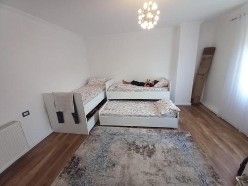een kamer met twee bedden en een persoon die erop ligt bij Vila Dervish ÇELA - MOKER in Pogradec