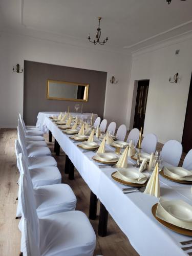 a row of tables in a room with white chairs at Hotel Leliwa in Leśna
