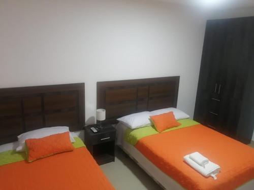 2 camas en una habitación con naranja y blanco en Departamento Suite Ciudad del Mar, en Manta