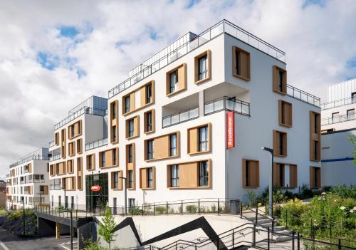 a white building with a red sign on it at Residhome Chartres in Chartres