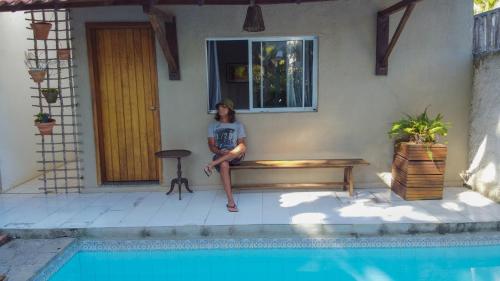 a woman sitting on a bench next to a house at Vila Ebert in Niterói