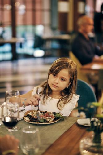 a little girl sitting at a table with a plate of food at Iberostar Waves Bahia - All Inclusive in Praia do Forte