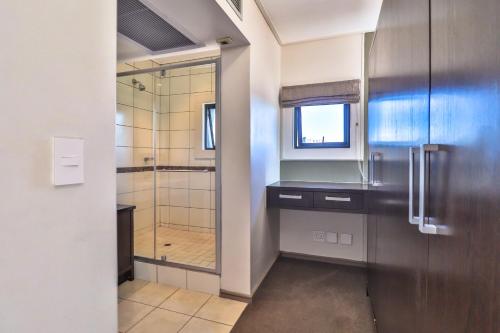 baño con ducha a ras de suelo y puerta de cristal en Manhattan Towers 506 by CTHA, en Ciudad del Cabo