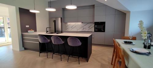 a kitchen with a island with purple stools at Noa's Suite in Opatija