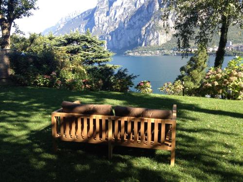 a wooden bench sitting in the grass near a lake at Casa Sull'Albero in Malgrate